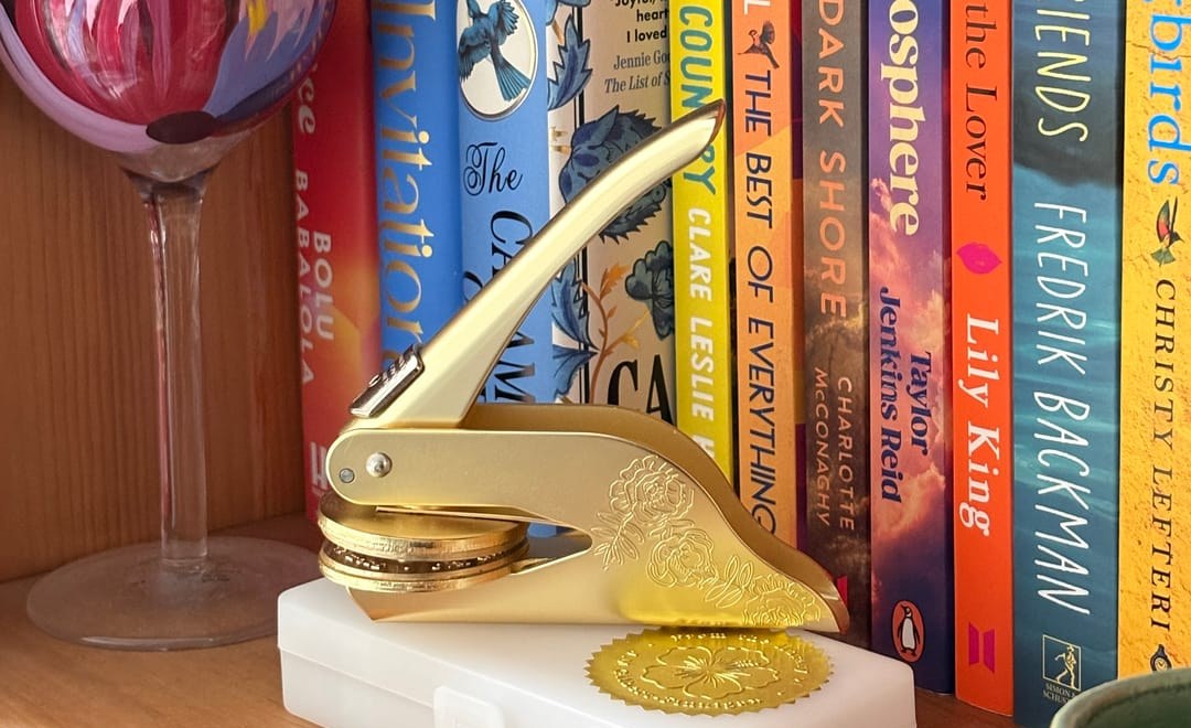A gold personalised book embosser and seal on a collector's bookshelf