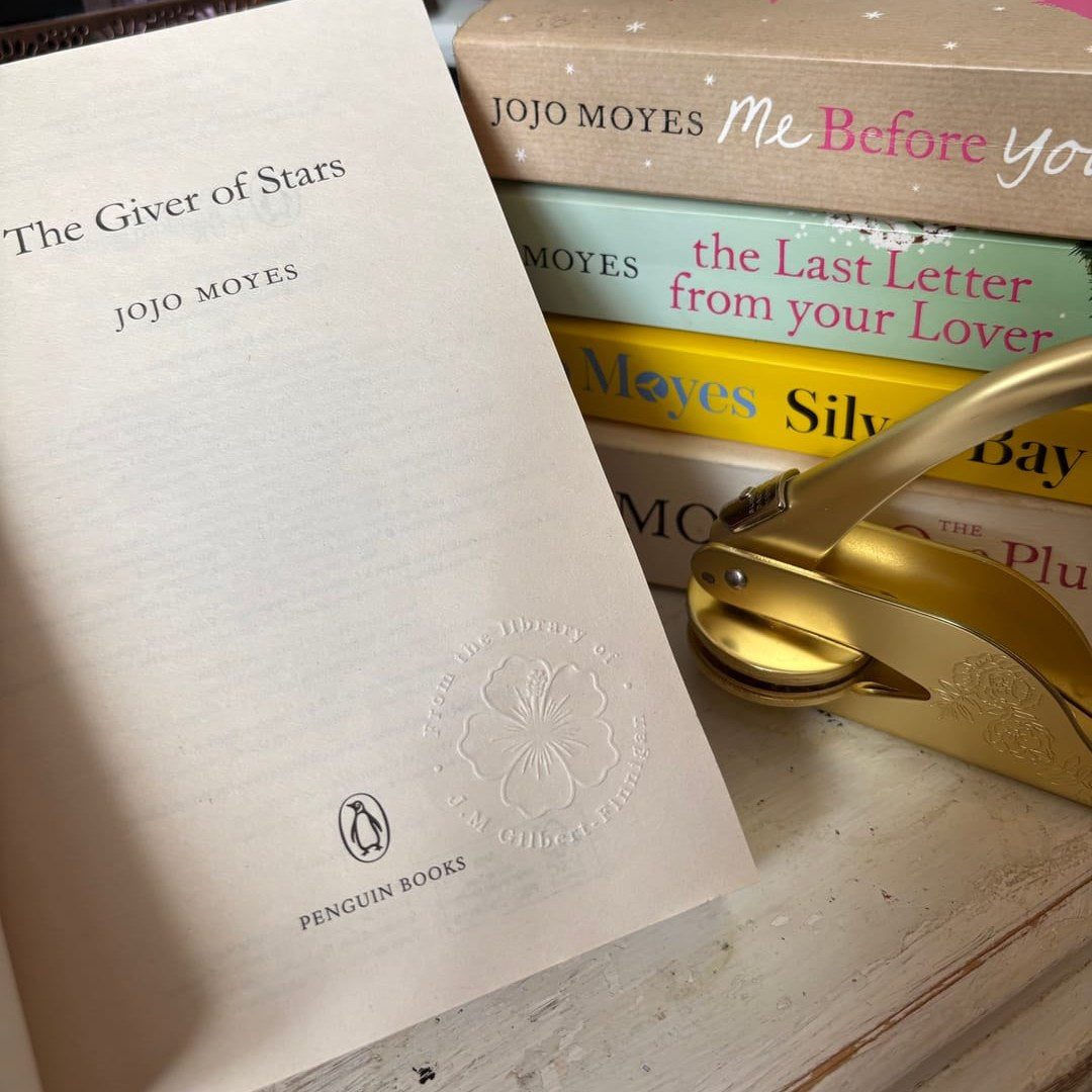 An embossed From the Library of seal on the title page of The Giver of Stars, beside a gold book embosser