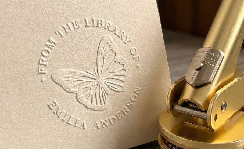 From the Library of embossed seal pressed into a page beside a brass book embosser