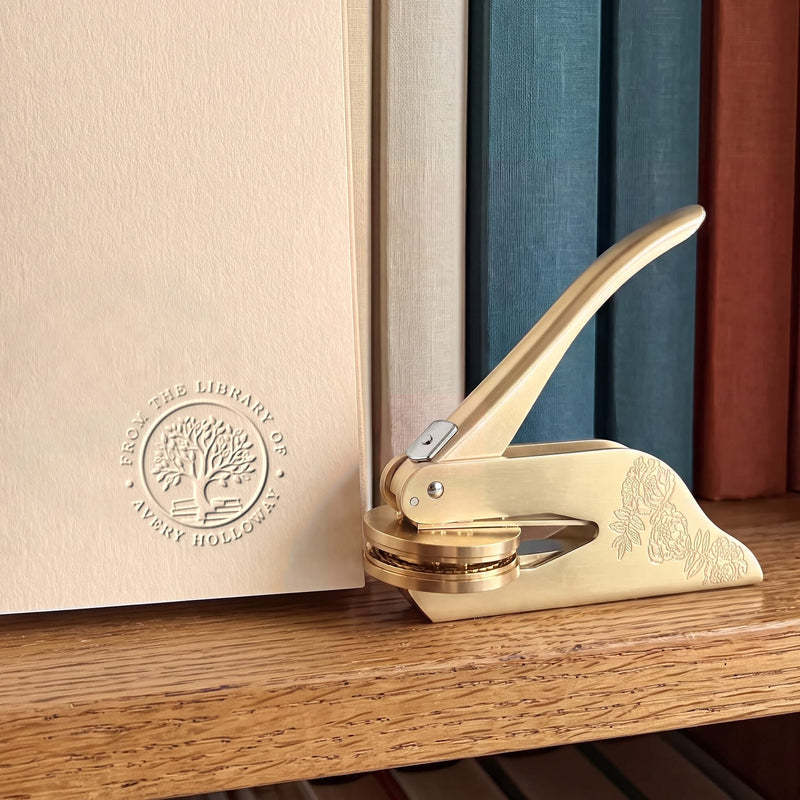 A gold personalised book embosser and seal on a collector's bookshelf
