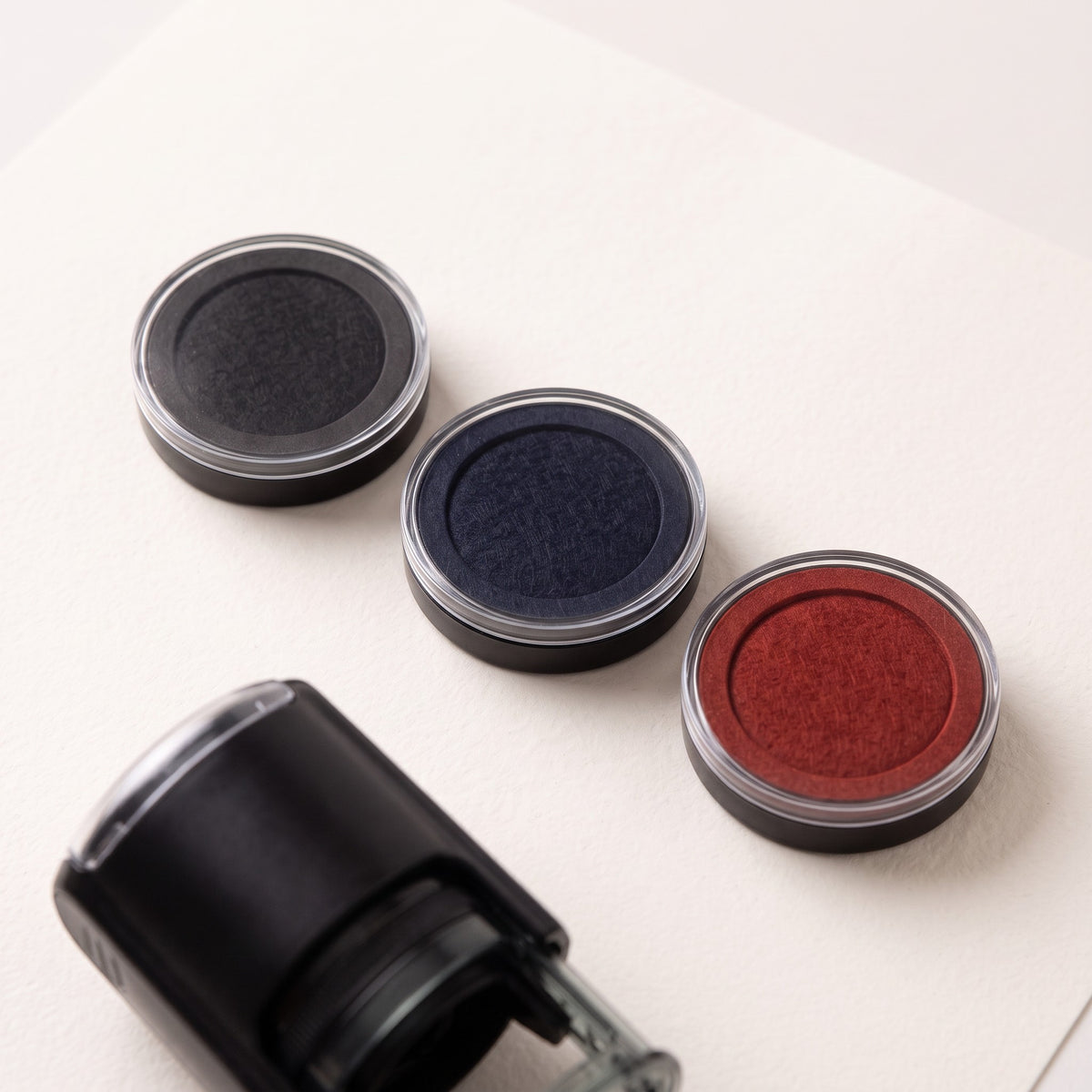 Almohadillas de recambio en negro, azul y rojo junto al sello automático