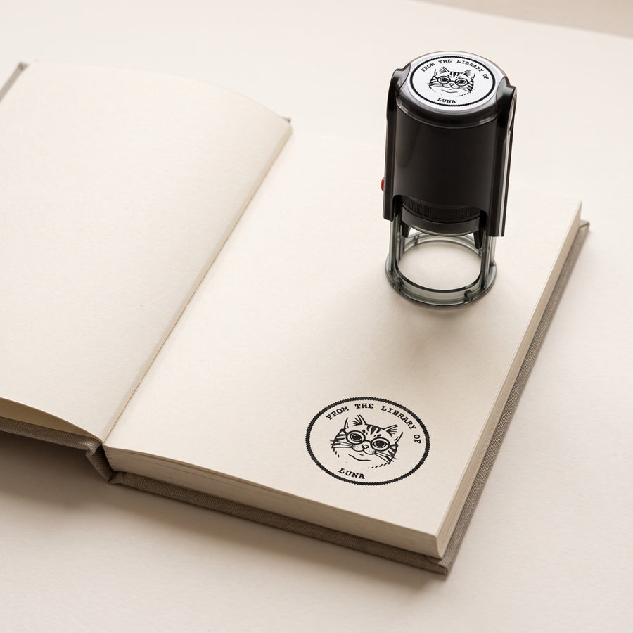 Personalised ex libris stamp with a cat portrait, printed in the corner of a book page, the stamp beside it